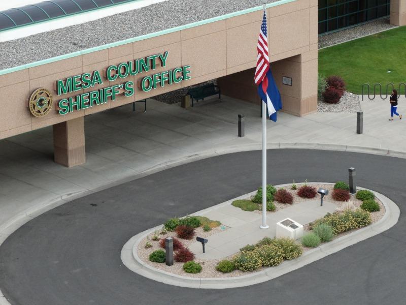 Aerial photograph of the outside of the Mesa County Sheriff's Office building showing a round-about driveway and flag pole with U.S. and State of Colorado flags.