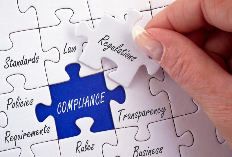 Concept photograph for Regulations. Jigsaw puzzle with terms Standards, Law, Policies, Requirements, Compliance, Transparency and Regulations piece held in hand.