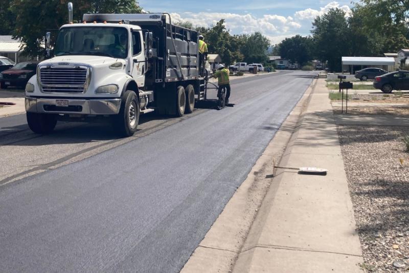 Large white truck working on new asphalt road.