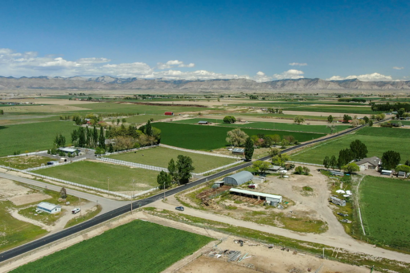 Aerial view of the Loma farming community featuring green fields, farm structures, and neatly arranged roads.