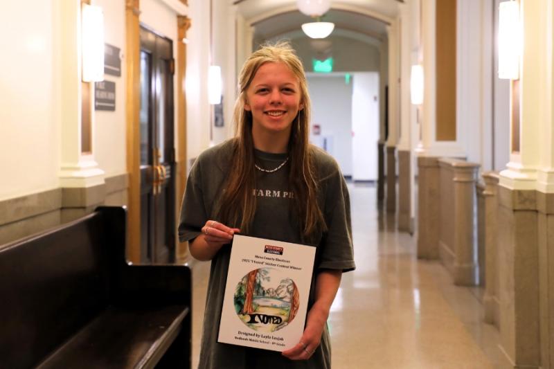 A child smiling holding a framed drawing. 