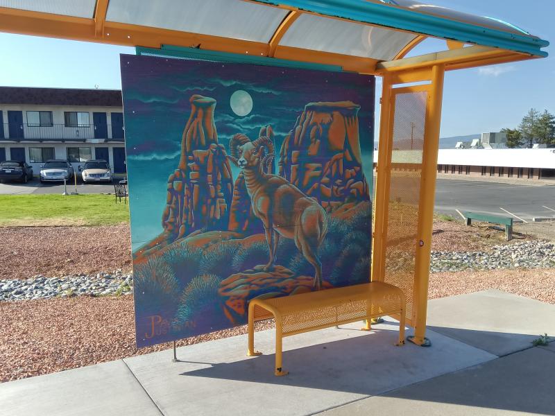 Photo of a Grand Valley Transit bus stop, with artwork featuring the Colorado National Monument and a bighorn sheep in the background.