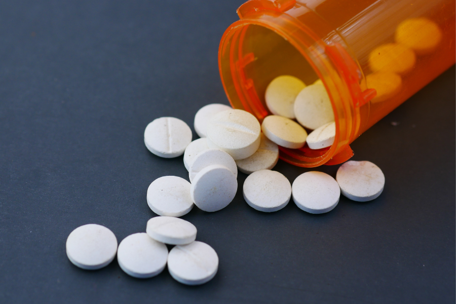 Pill bottle containing small, white, circular pills.