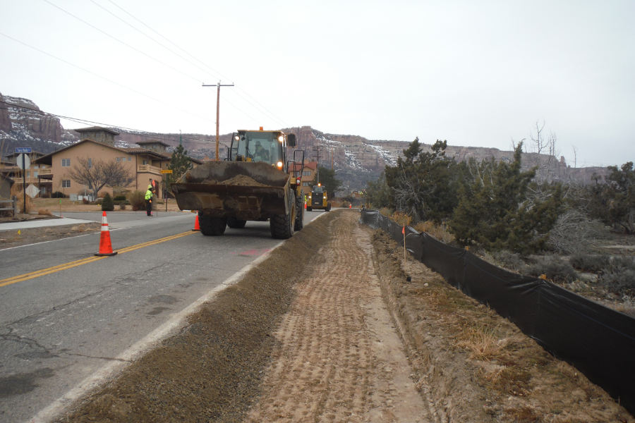 Two construction vehicles driving in opposite directions working on South Broadway Shoulder Project.