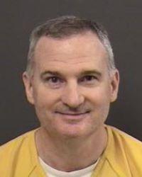 Michael F. Blagg in yellow prison jumpsuit