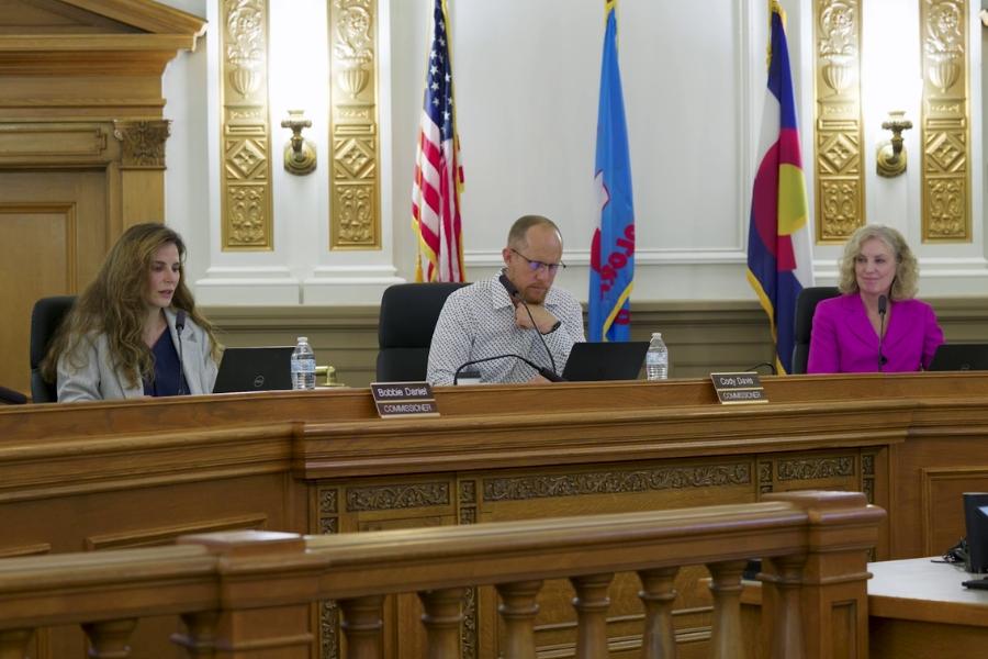 Board of Mesa County Commissioners sitting in public hearing room. 