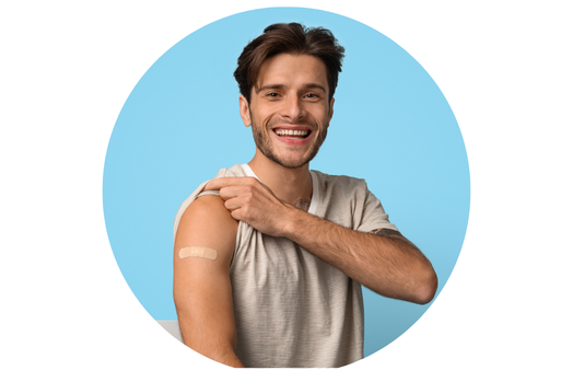 Picture of man with brown hair, wearing a tan shirt. He is lifting up the sleeve on one arm showing a bandaid on his arm.