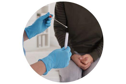 Person wearing dark brown sweater sitting on a doctor table. Gloved hands holding a testing swab and kit.