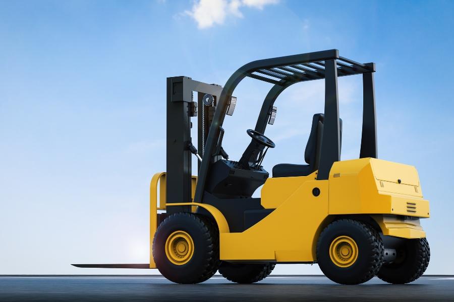 Yellow pneumatic tire forklift in front of blue sky.