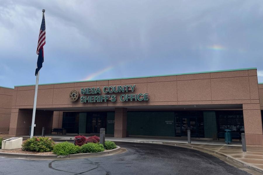Outside of Mesa County Sheriff's Office. Brick building with green sign reading, "Mesa County Sherriff's Office. 