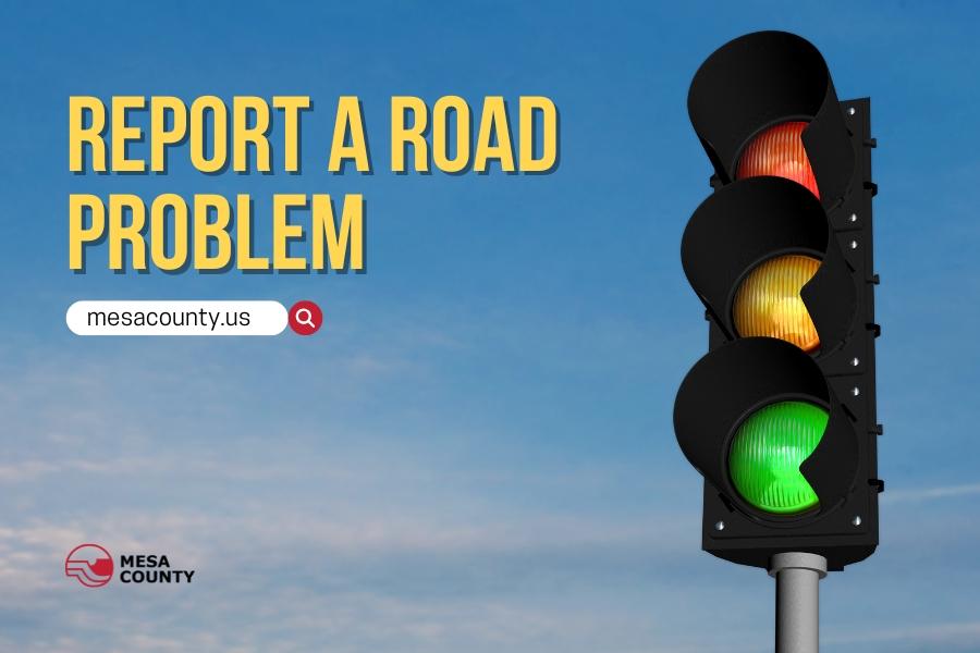 Traffic light with red light at the top, yellow in the middle, and green on the bottom with yellow text reading, "report a road problem," and a white and red search bar below that reading, "mesacounty.us," and the red and black Mesa County logo below that. 