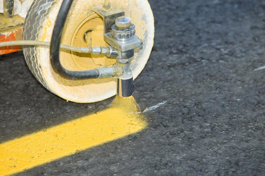 Equipment spraying yellow line of paint on a road. 