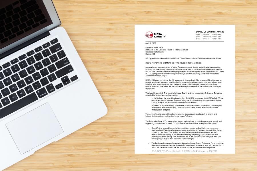 A letter sitting on a light wood desk next to a laptop. 