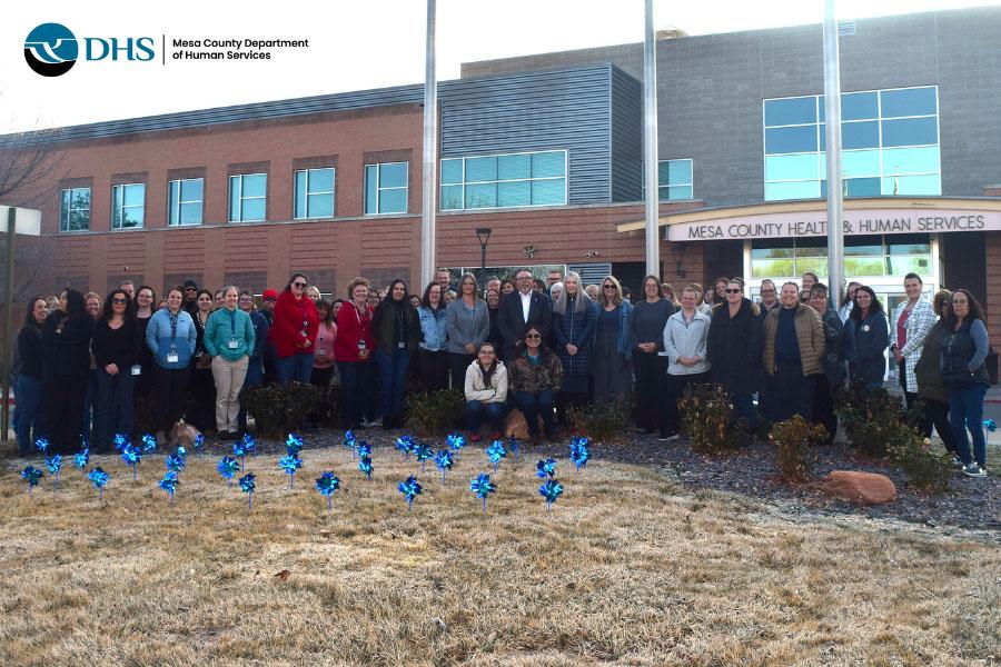 Human Services staff in front of HHS building with pinwheels planted