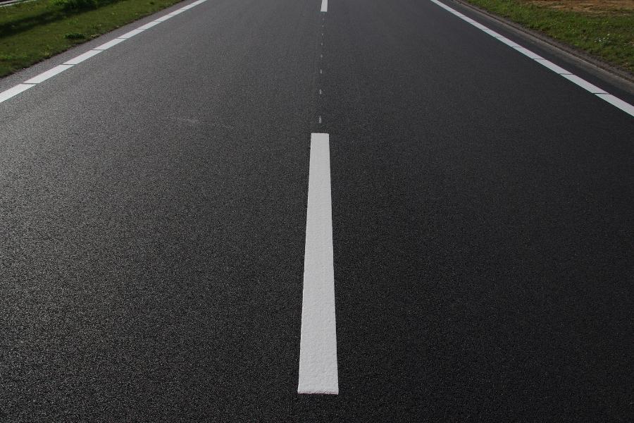 Newly paved road with white stripes down the middle. 