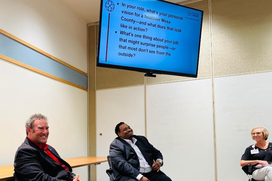 Two people sitting under a presentation screen smiling. 