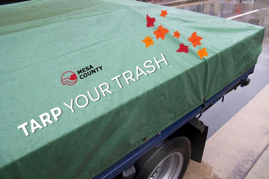 A trailer covered by a green tarp with white text reading, tarp your trash, with the Mesa County logo and leaves. 