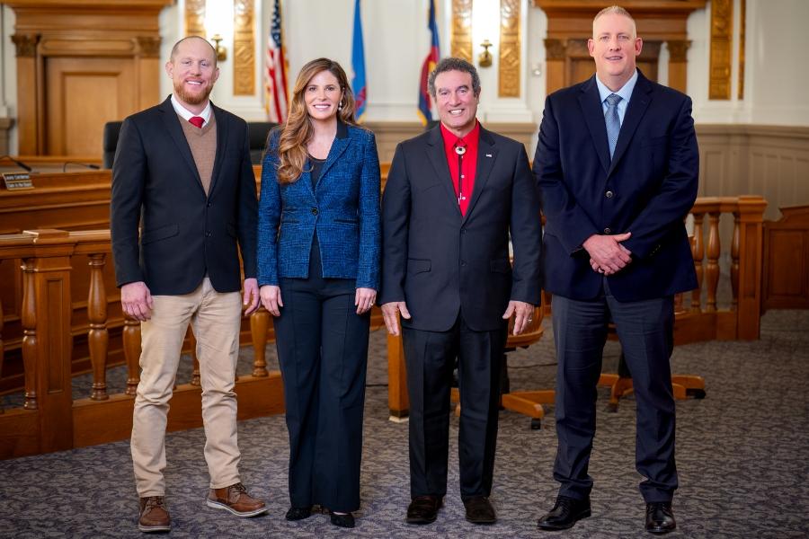 Four people smiling next to each other. 