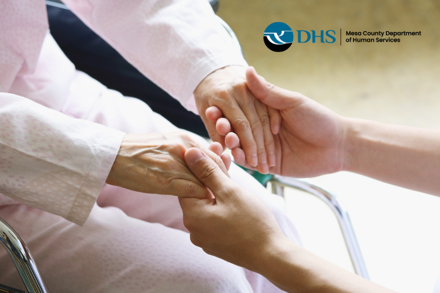 Elder holding hands with caretaker with MCDHS logo in top right corner
