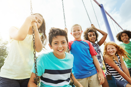 Group of children playing on a swingset.