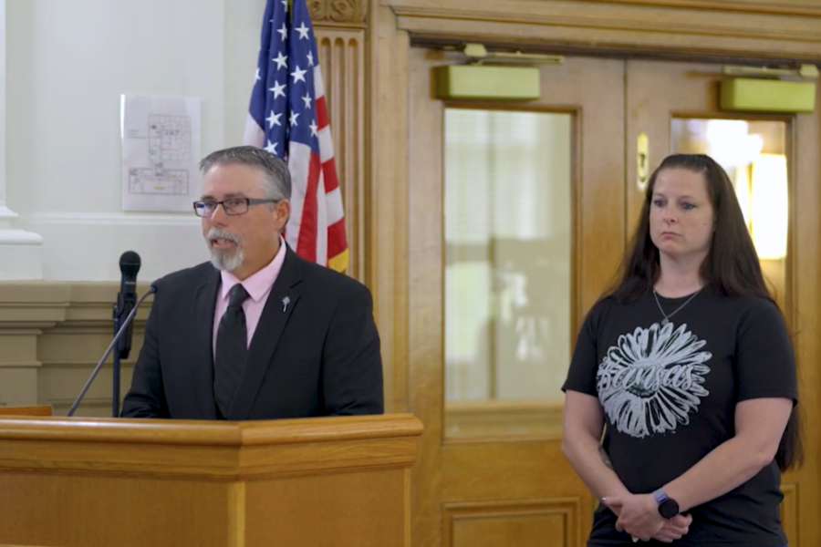 Mesa County Department of Human Services Child Welfare and Adult Protection Division Director Joe Kellerby speaks at a Board of County Commissioners public hearing while foster parent Allie Johnson stands beside him as the family is recognized for receiving a statewide foster care honor.
