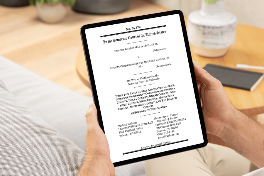 A person holds a tablet displaying the cover page of an amicus brief filed in a case before the U.S. Supreme Court. The brief includes the Associated Governments of Northwest Colorado and several western Colorado counties, including Mesa County, and is shown in a home or office setting.